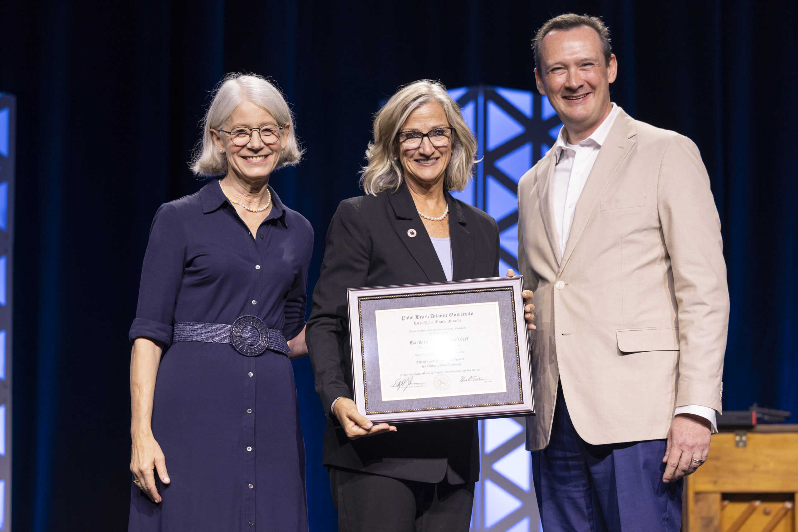 Barbara VanderWerf smiling and holding her award on stage