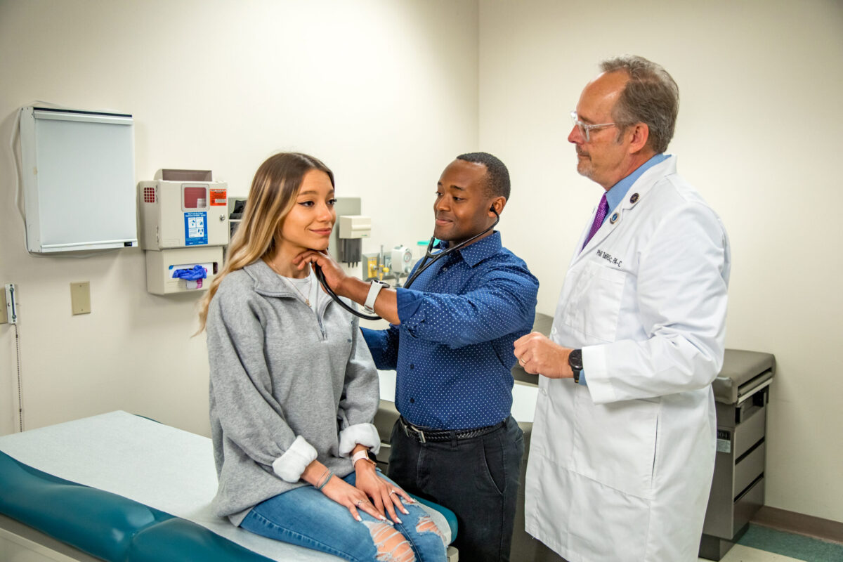 A photo of two doctors using a stethoscope on a patient