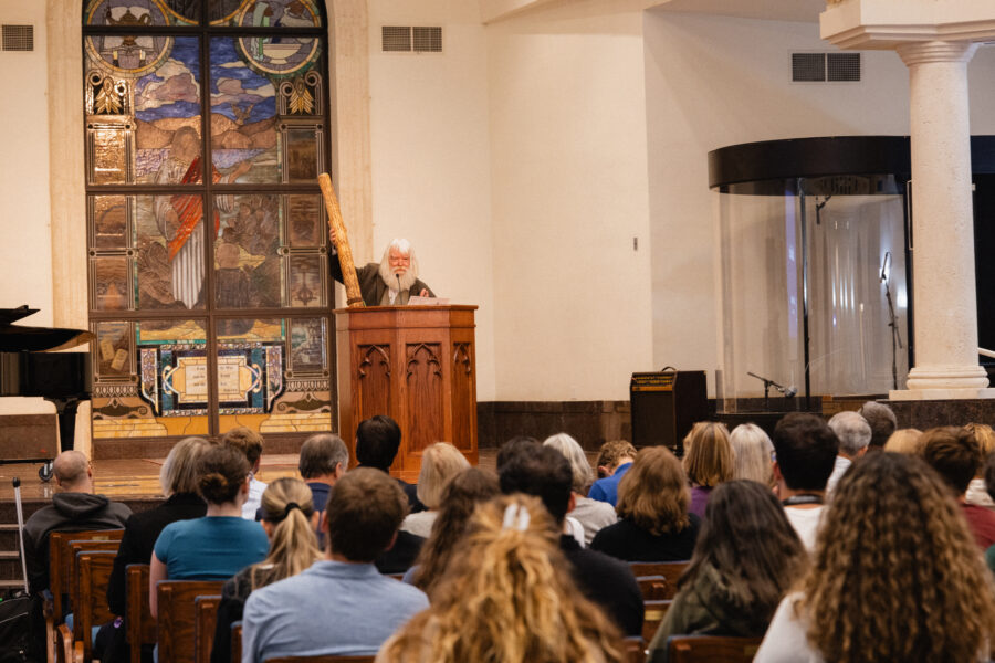 Malcolm Guite holds a rainstick while lecturing in PBA DeSantis Family Chapel.